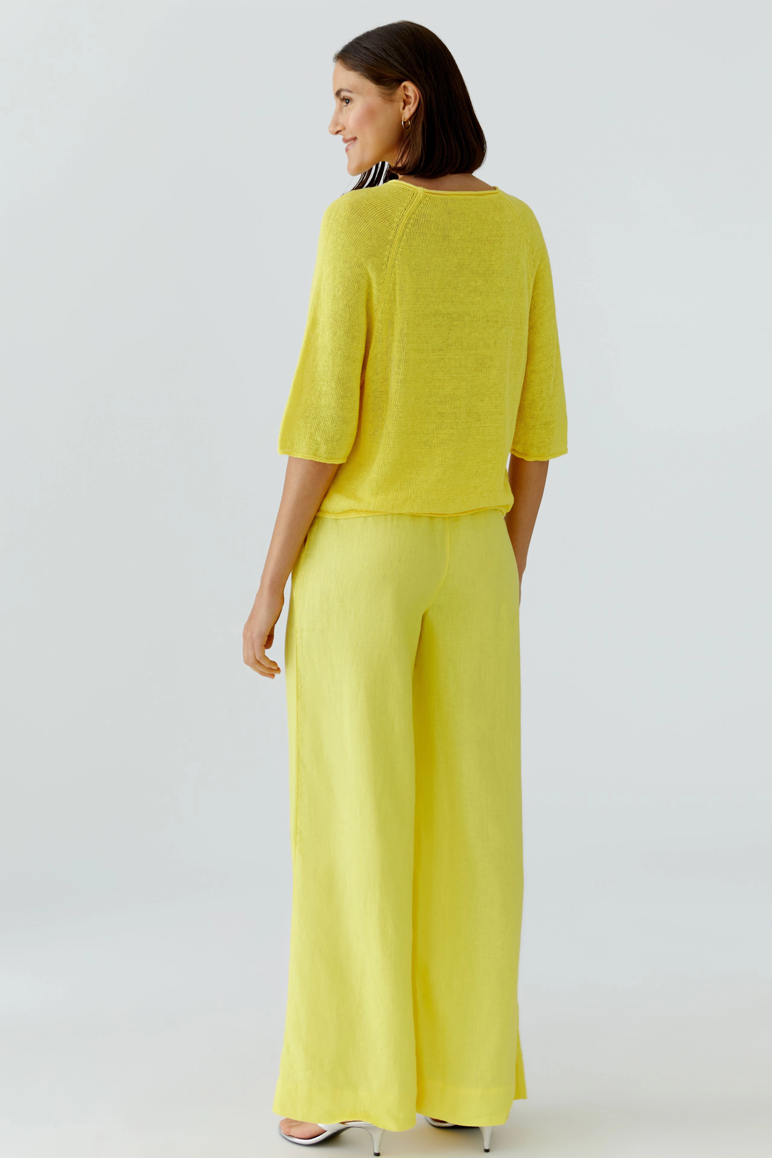 Casual women's pullover: Woman in a yellow pullover and matching wide-leg pants, standing confidently.