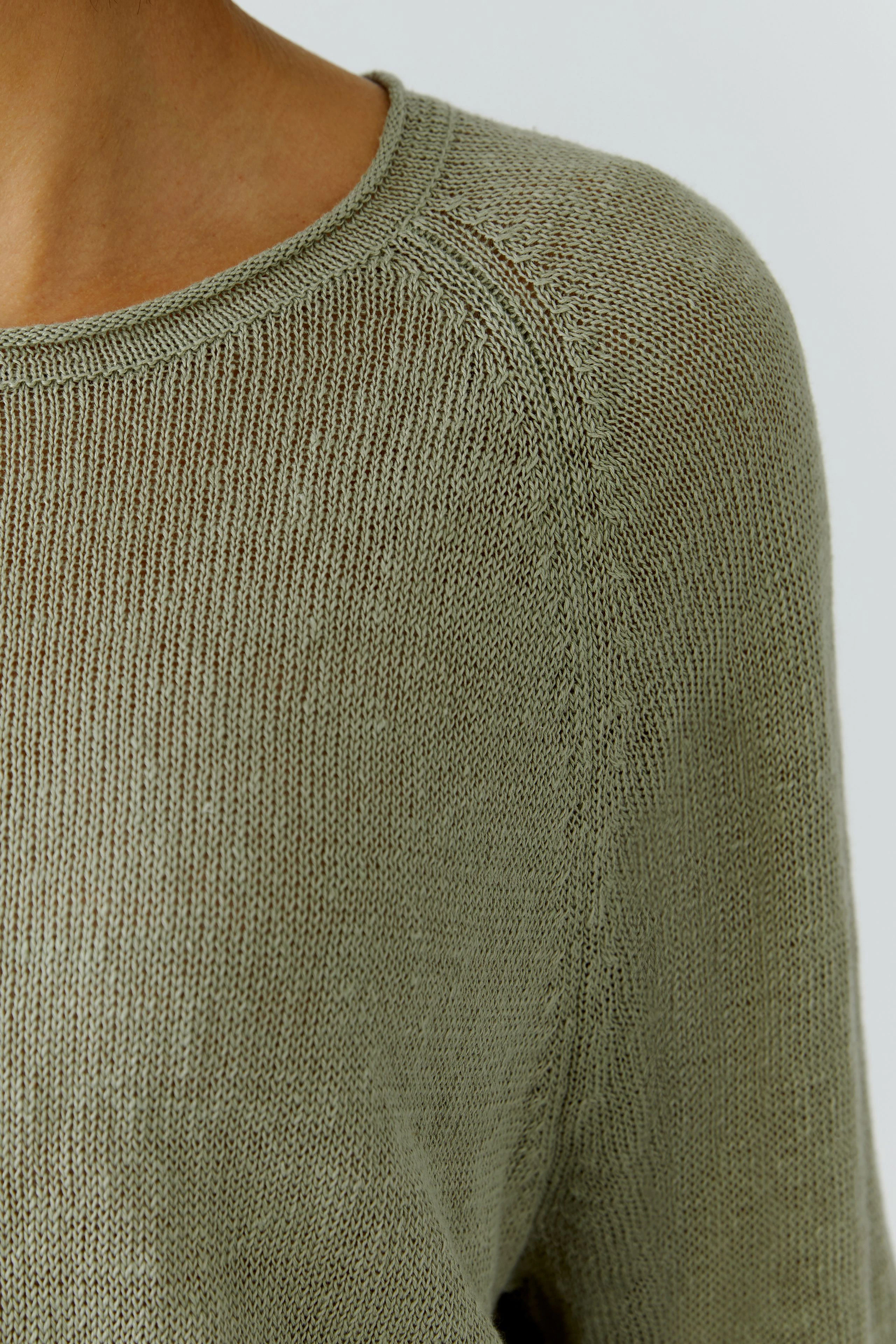 Casual pullover: Woman in a light green knit pullover with a relaxed fit, showcasing texture and comfort.