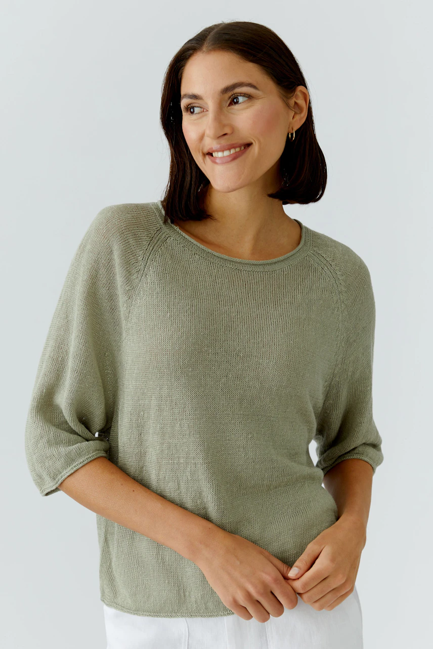 Lässiger Damen-Pullover: Frau im grünen Pullover mit 3/4-Ärmeln lächelt entspannt.