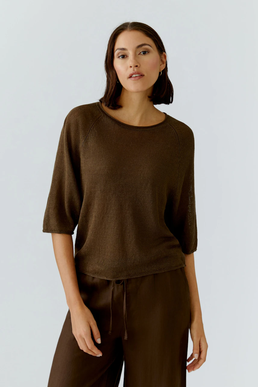 Lässiger Damen-Pullover: Frau im braunen Pullover mit Dreiviertelärmeln und passender Hose, entspanntes Auftreten.