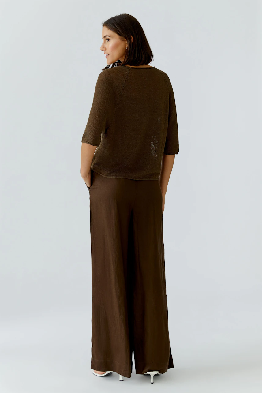 Damen-Pullover: Frau im lockeren, braunen Pullover und passender Hose, seitlich stehend.