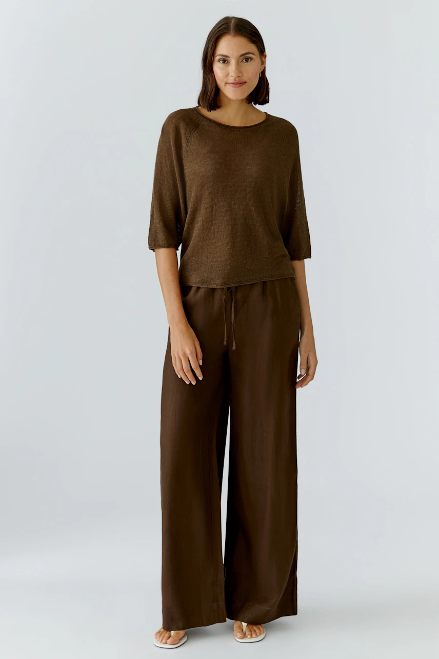 Damen-Pullover: Frau im braunen Pullover mit halblangen Ärmeln und passender Hose, entspanntes Outfit.