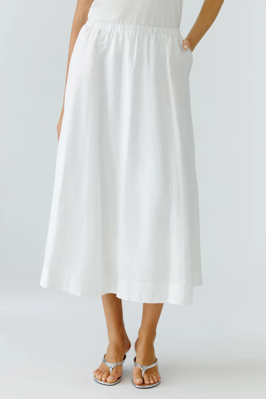 A-Linien-Rock: Frau in weißem, knöchellangem Rock mit elastischem Bund und Sandalen.