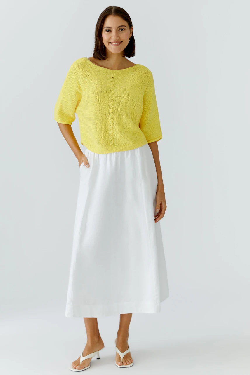 A-Linien-Rock: Frau im weißen Rock und gelbem Pullover, lässig und sommerlich.