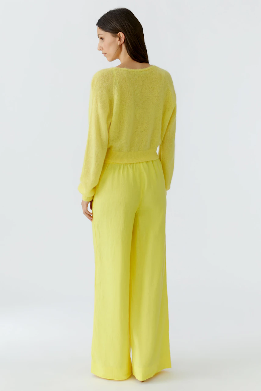 Woman in yellow cardigan and matching pants, viewed from behind. Casual and cozy look.