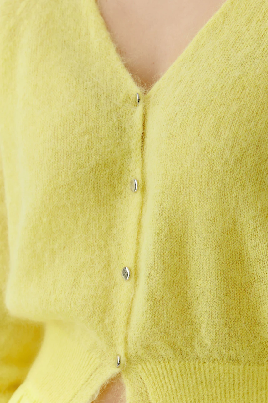 Bright yellow cardigan: Close-up of a soft knit cardigan with button details, worn by a woman.