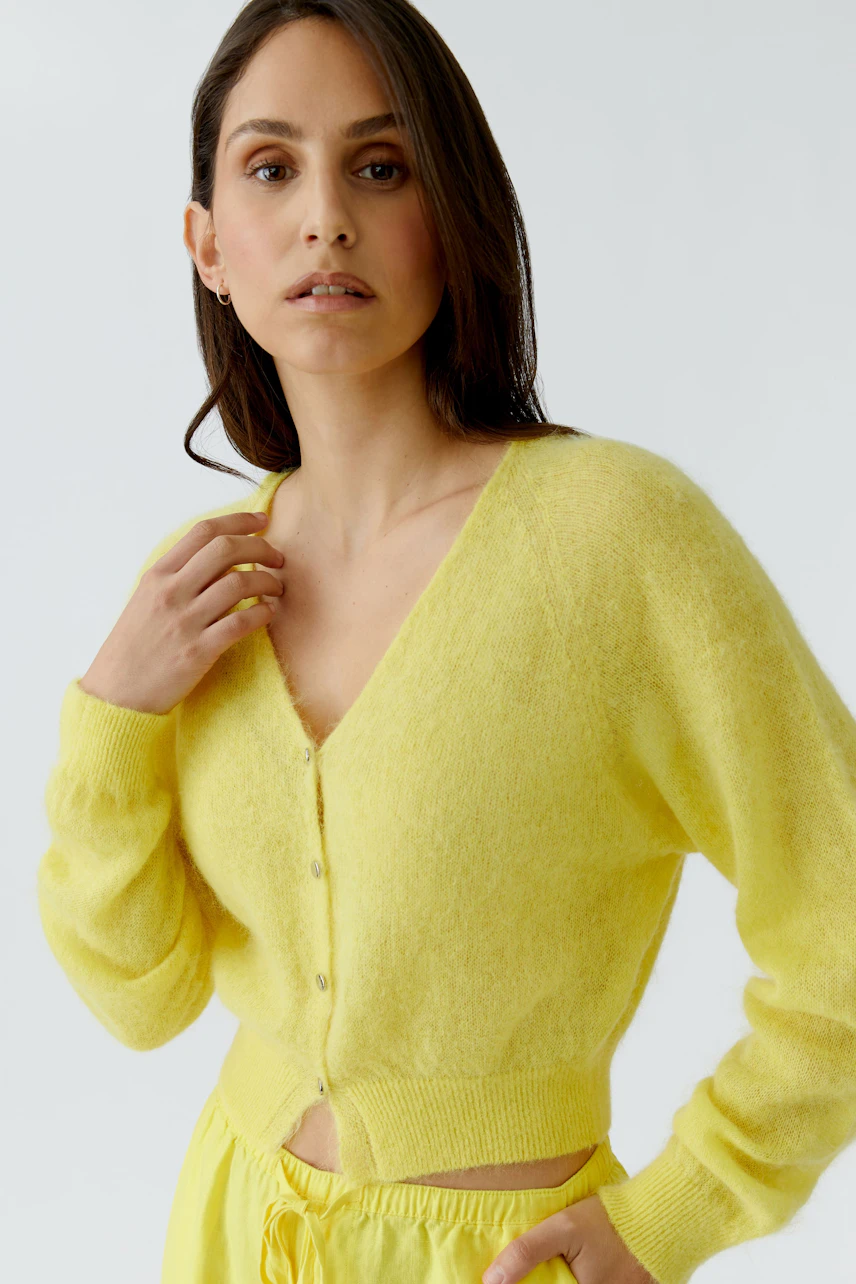 Yellow cardigan: Woman in a soft yellow knit cardigan with buttons, paired with matching pants.