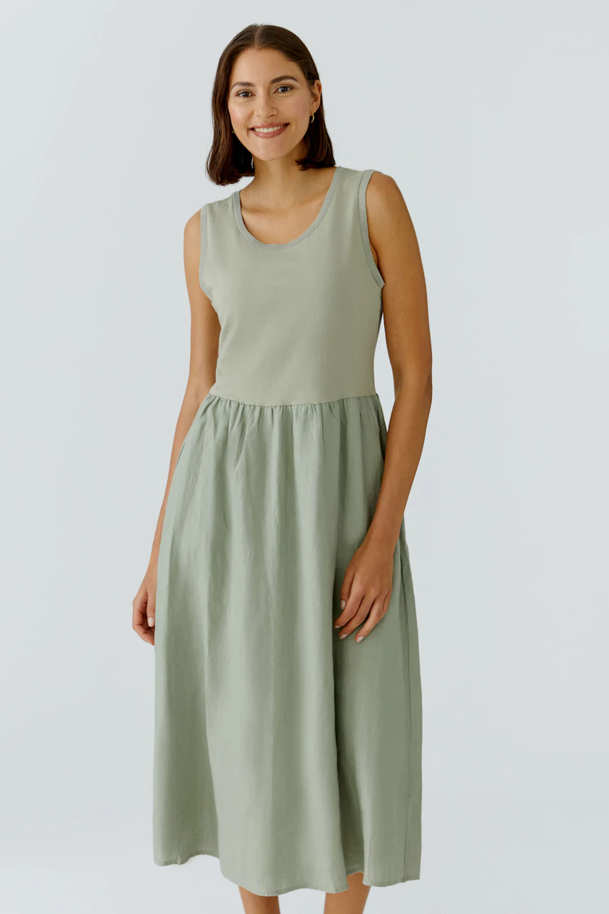 Casual midi dress: Woman in a sleeveless, light green midi dress, smiling confidently.