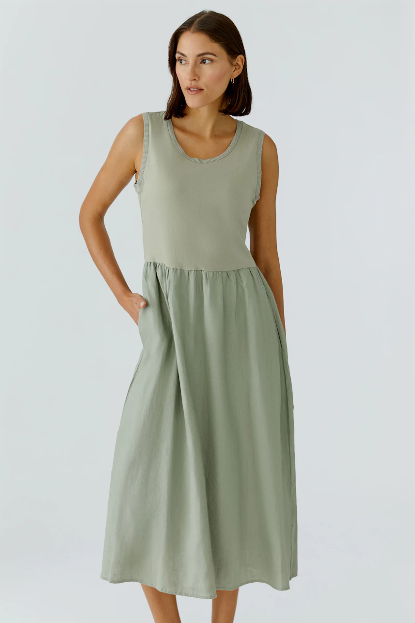 Casual midi dress: Woman in sleeveless, light green dress with pockets, looking to the side.