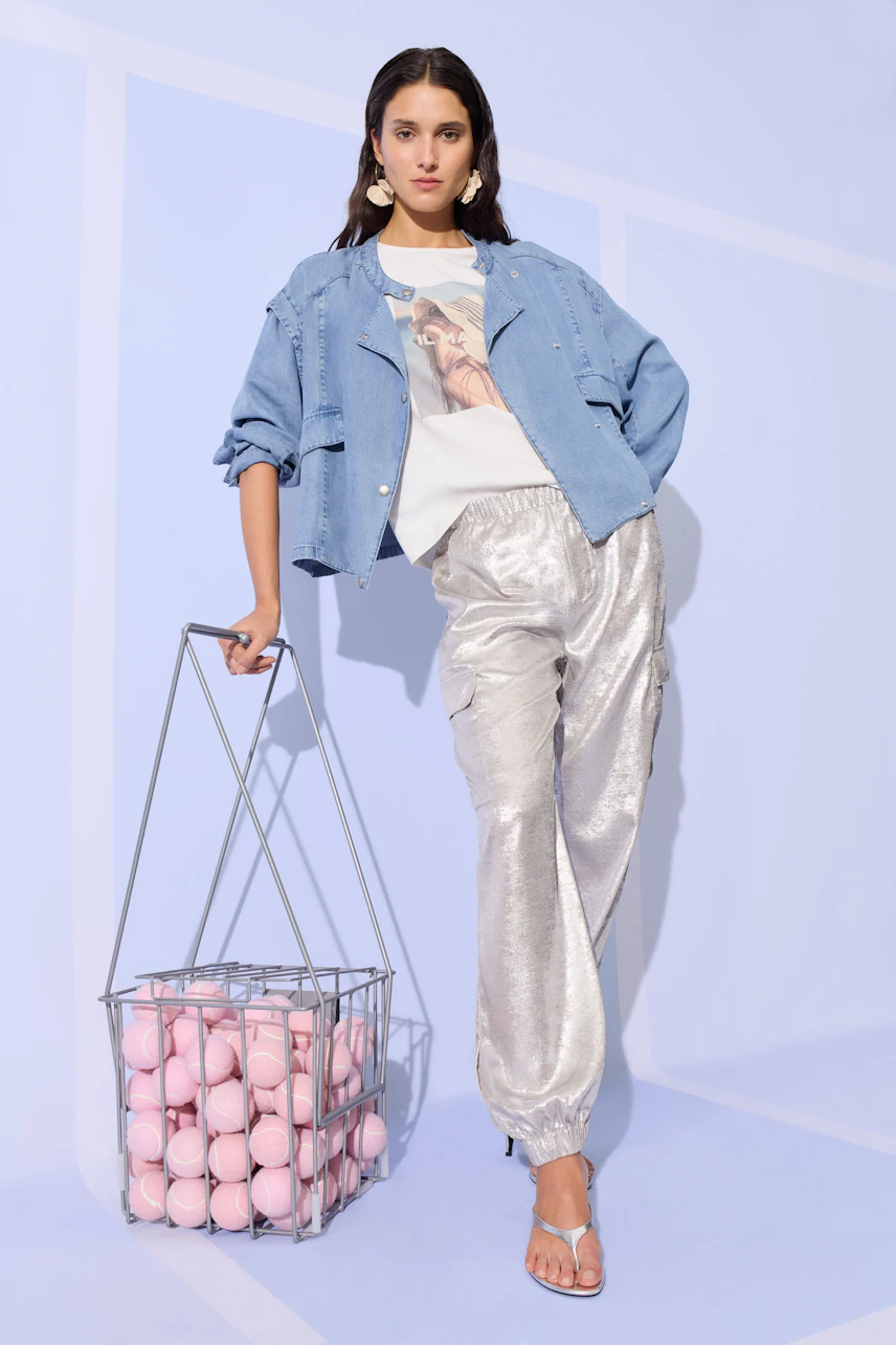 Casual women's T-shirt: Woman in graphic tee with denim jacket and shiny pants, holding a basket of pink balls.