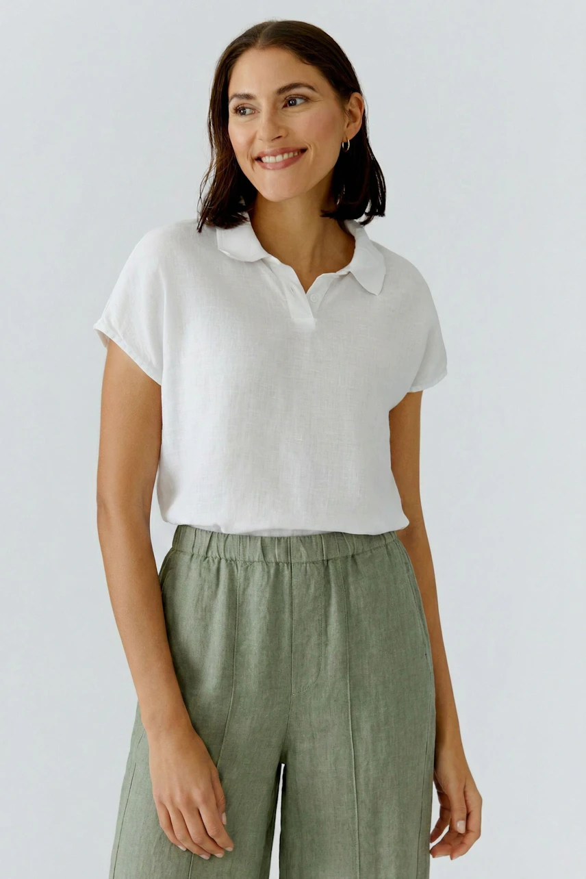 Casual women's blouse: Woman in a white blouse with short sleeves and a relaxed fit, smiling confidently.