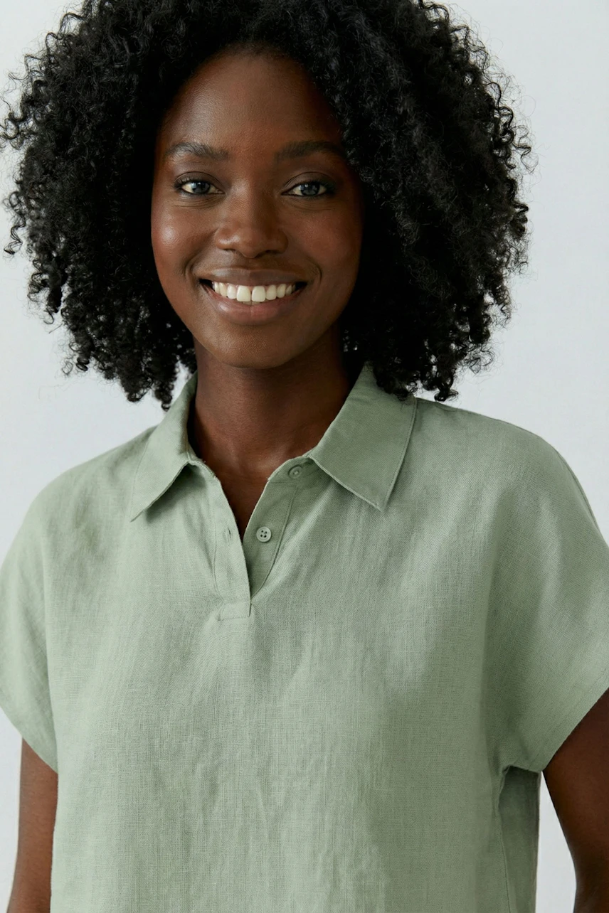 Casual blouse: Smiling woman in a light green blouse with short sleeves and a relaxed fit.