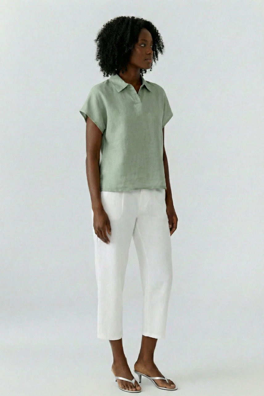 Casual blouse: Woman in a green blouse with short sleeves and white pants, standing confidently.
