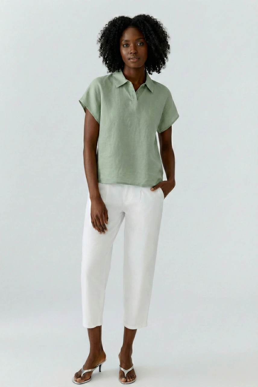 Casual blouse: Woman in a green blouse and white pants, standing confidently.