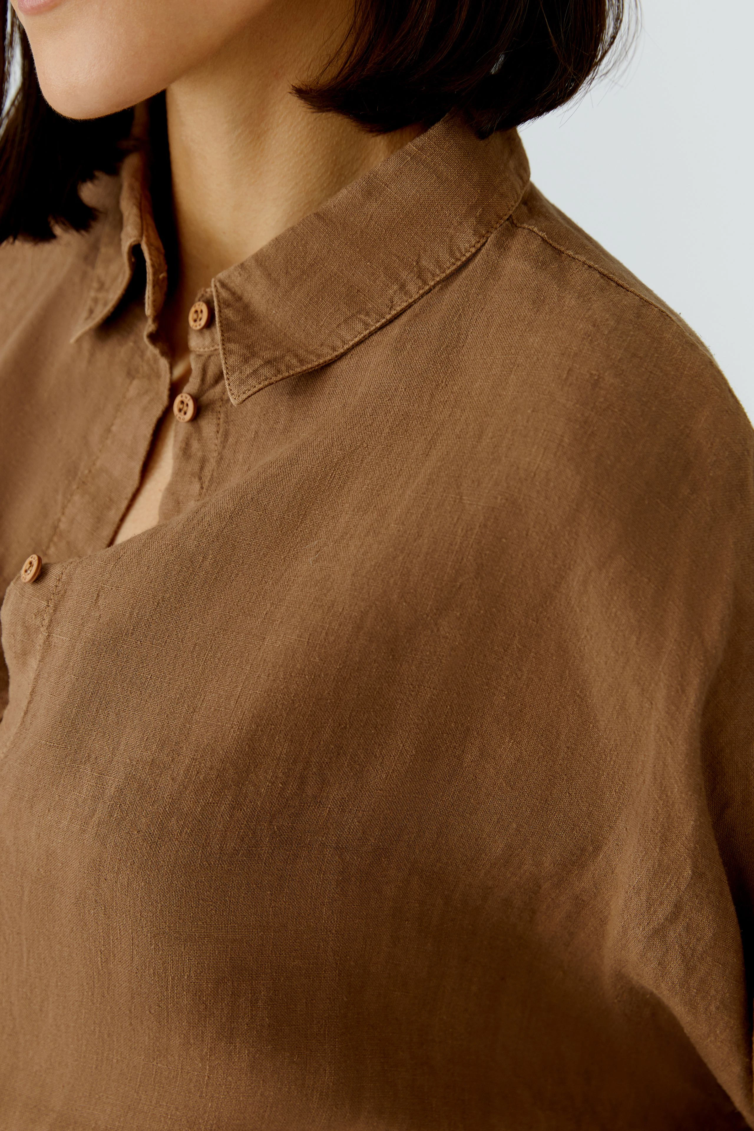 Braune Damen-Bluse: Frau trägt lockere Bluse mit Knopfleiste und klassischem Kragen.