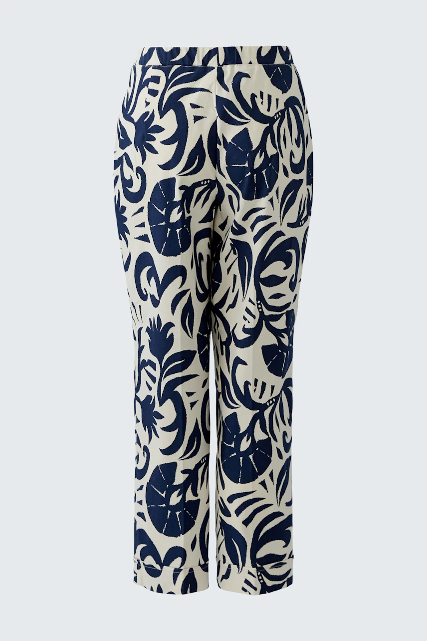 Women's pants with bold navy leaf print on white fabric, offering a stylish and comfortable fit.