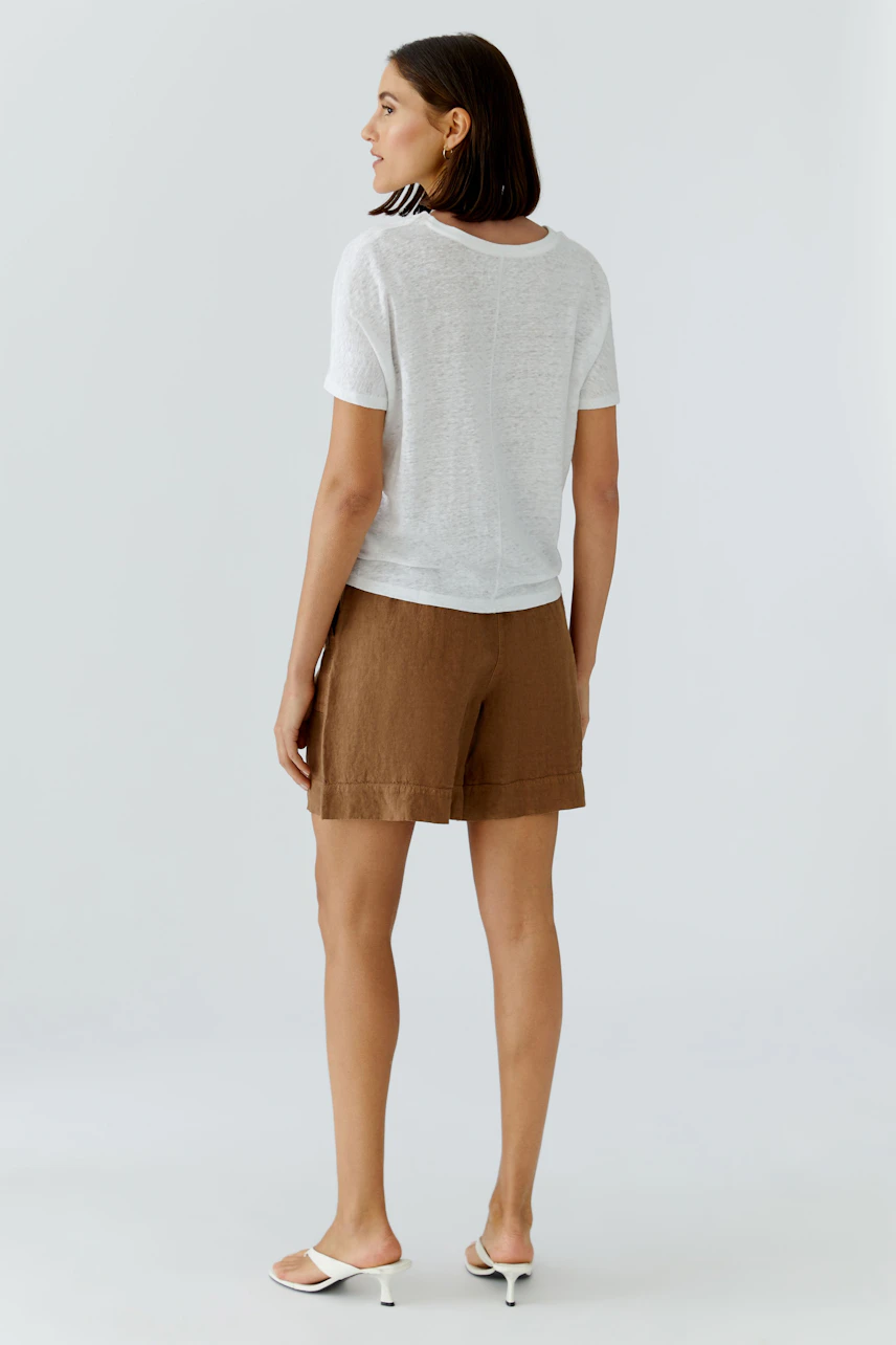 Casual women's T-shirt: Woman in a white T-shirt and brown shorts, standing confidently.
