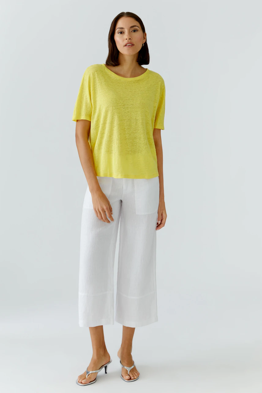 Casual women's T-shirt: Woman in a yellow T-shirt and white pants, standing confidently.
