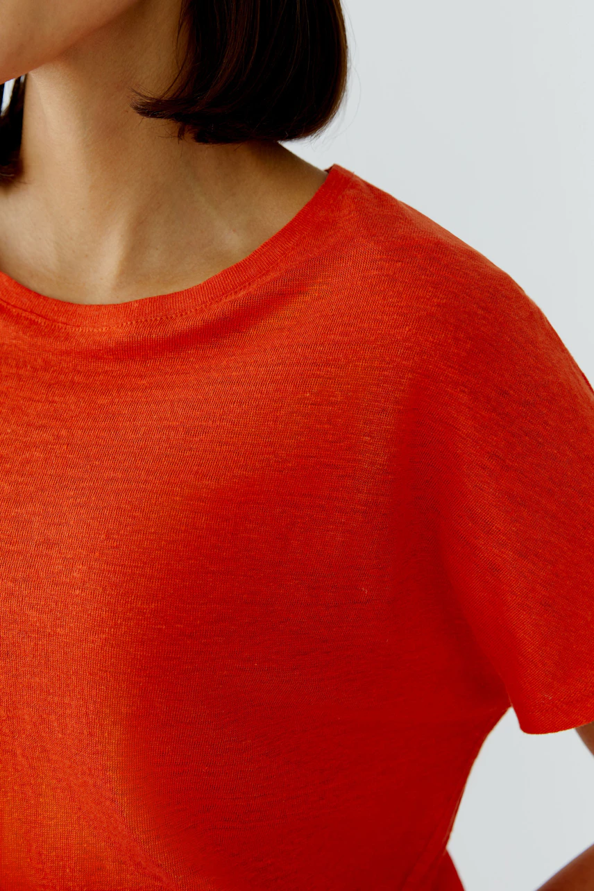 Rotes Damen-T-Shirt: Frau trägt ein schlichtes, leuchtend rotes T-Shirt mit kurzen Ärmeln.