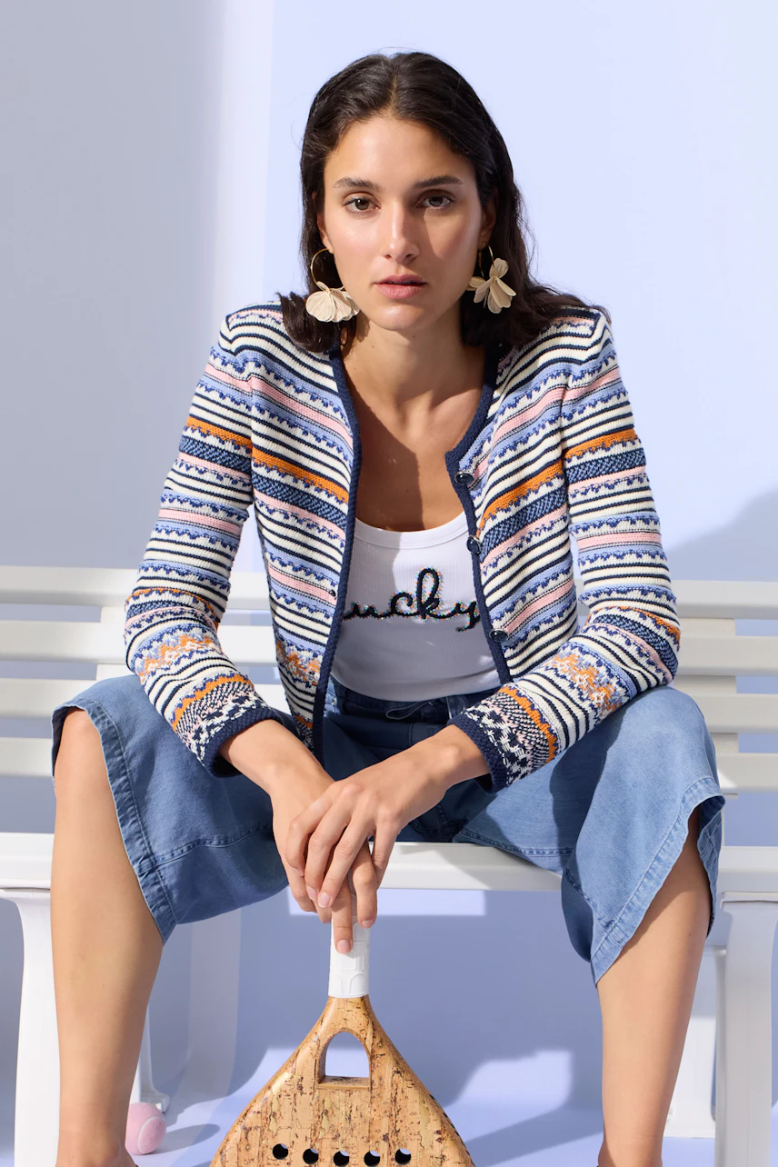 Casual tank top: Woman in a white tank top with text, paired with a patterned jacket and denim culottes.