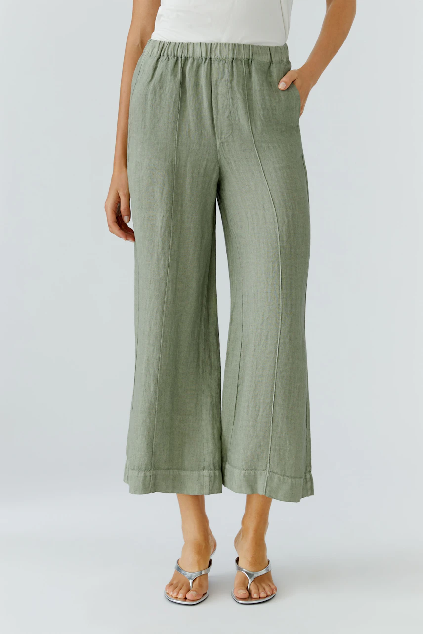 Lässige Damen-Hose: Frau in grüner, weiter Hose aus Leinen, kombiniert mit weißen Sandalen.