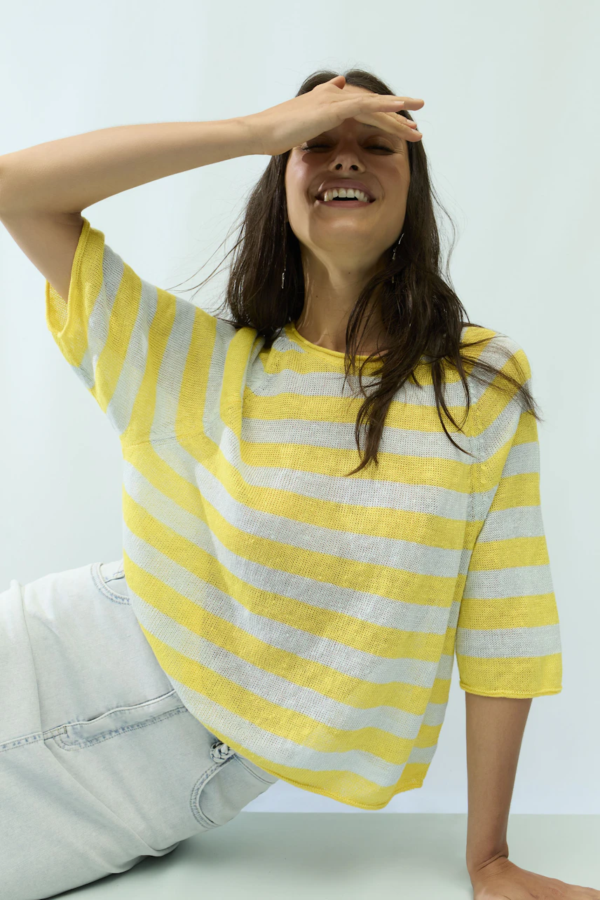 Casual jeans skirt: Woman in a light denim skirt and yellow striped top, smiling and relaxed.