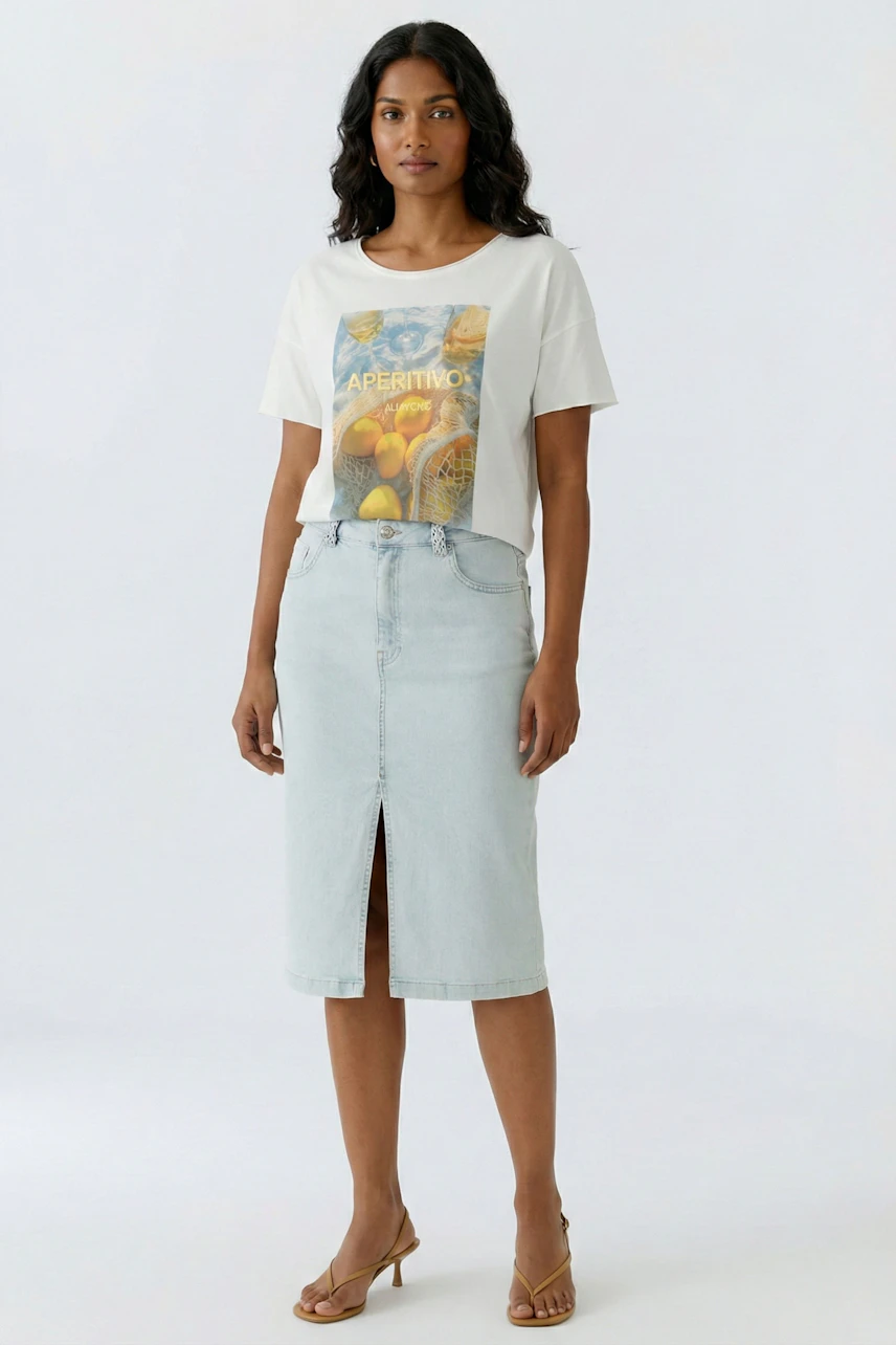 Casual denim skirt: Woman in light blue jeans skirt and graphic tee, standing confidently.
