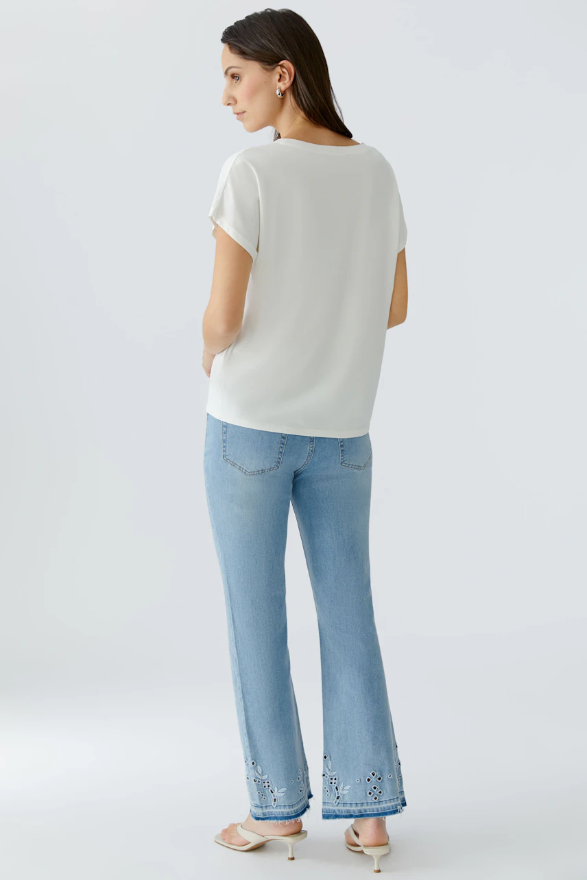 Weißes Damen-T-Shirt: Frau im locker fallenden T-Shirt und hellblauer Jeans von hinten zu sehen.