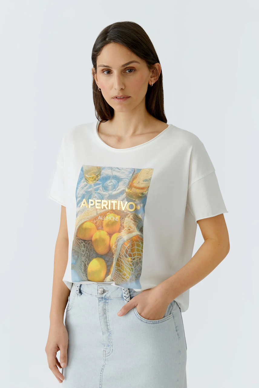 Damen-T-Shirt: Frau im weißen T-Shirt mit buntem Print und lässiger Haltung.