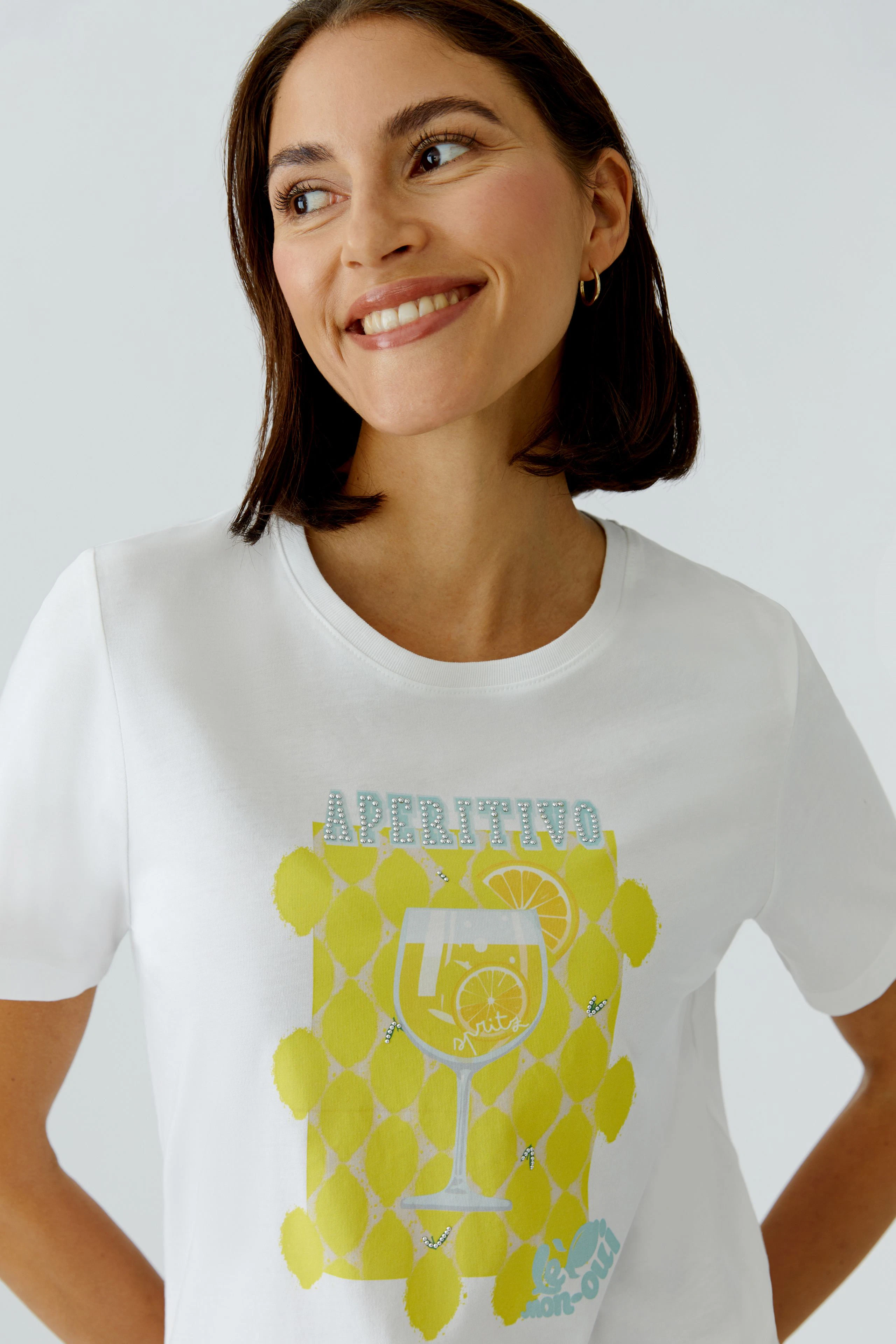 Casual women's T-shirt: Smiling woman in a white T-shirt with yellow graphic print.
