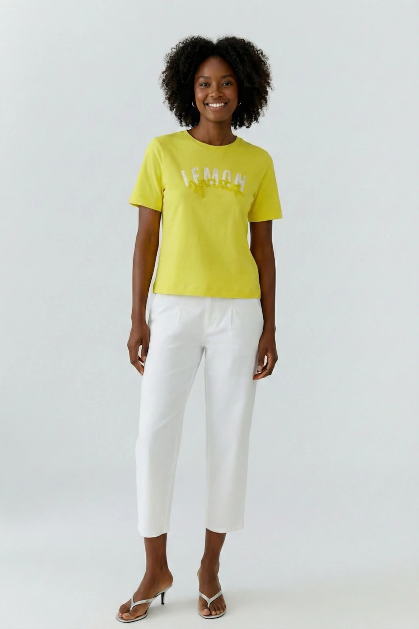 Casual T-shirt: Woman in yellow T-shirt with "Lemon" print, paired with white pants, smiling confidently.