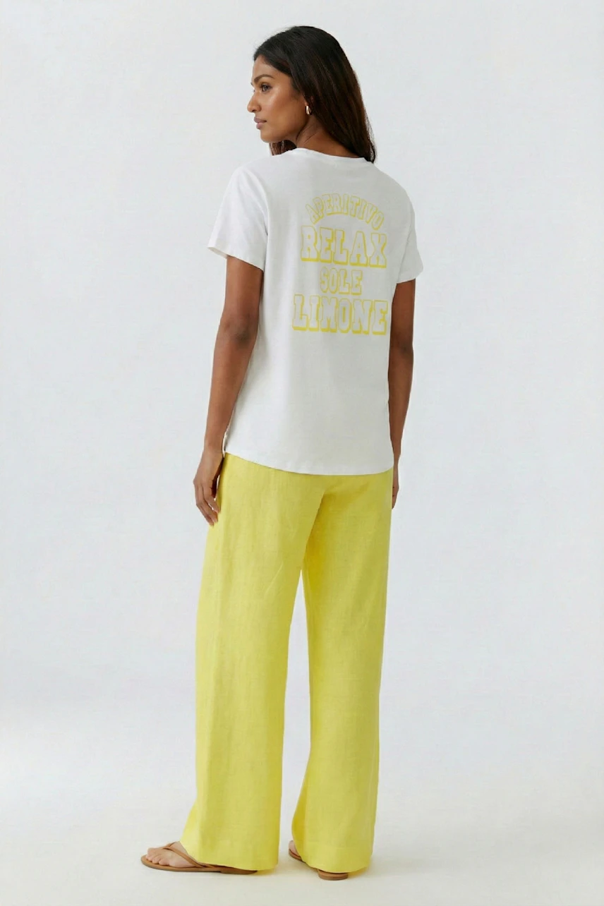Damen-T-Shirt: Frau im weißen T-Shirt mit gelbem Schriftzug und gelber Hose, entspanntes Design.