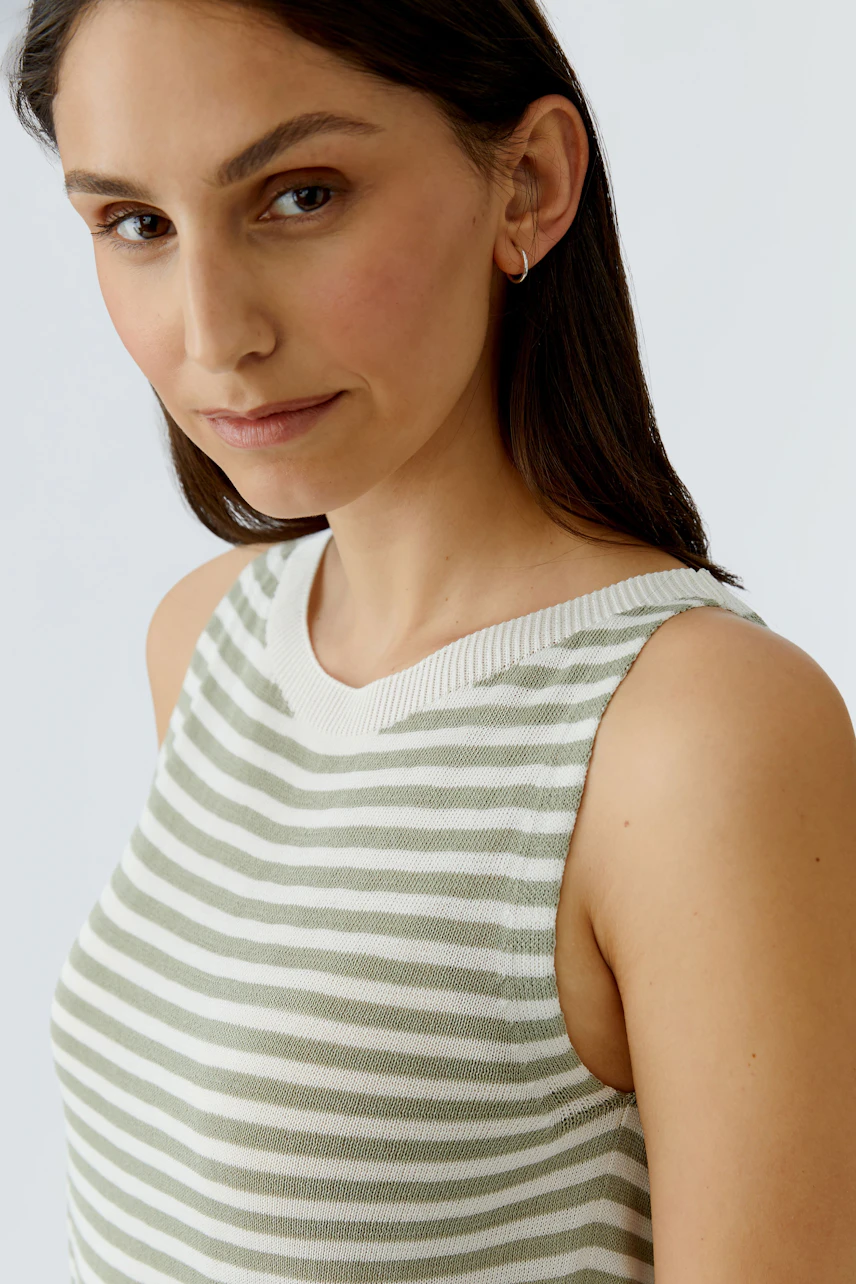 Gestreiftes Damen-Top: Frau im ärmellosen, grün-weiß gestreiften Top mit dezentem Lächeln.