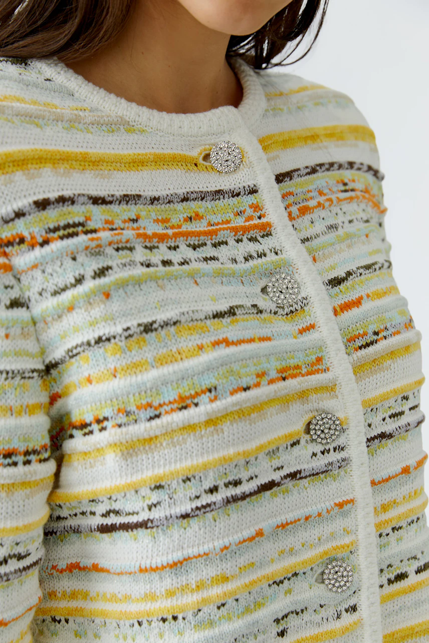 Frau in bunter Strickjacke mit Knöpfen, gelb-weiß gestreift, zeigt lebendiges Design.