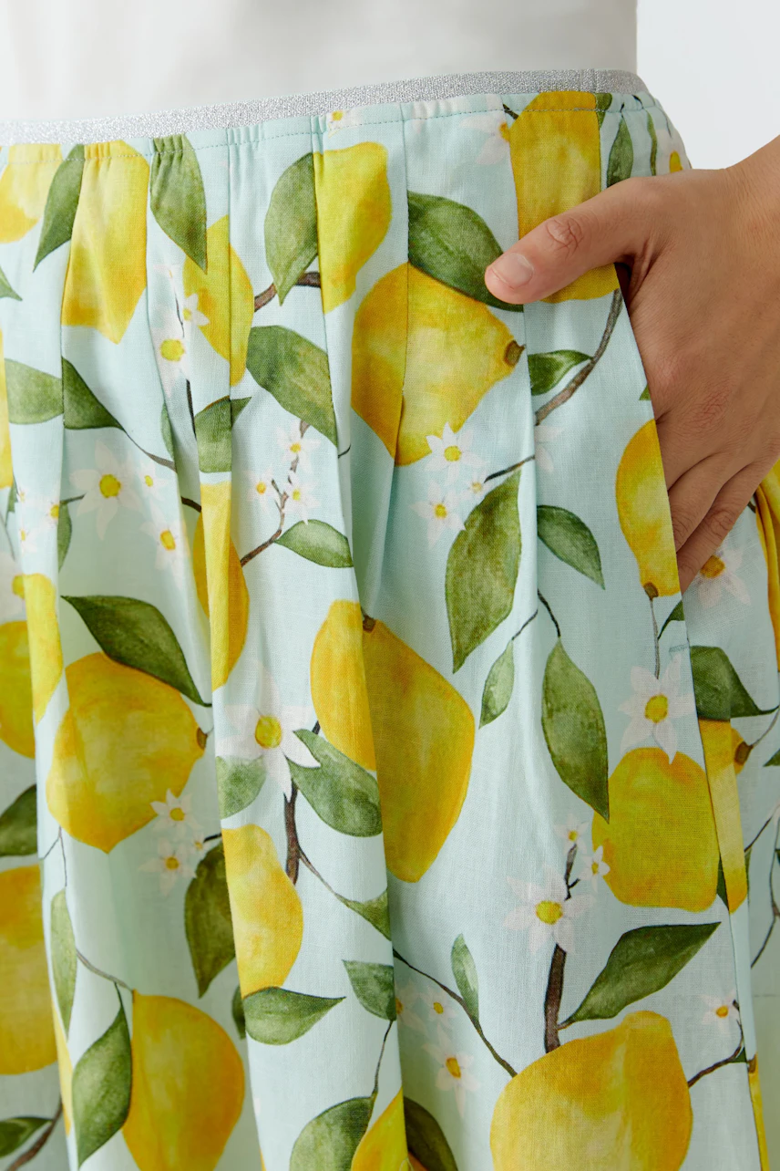 Faltenrock mit Zitronenmuster: Frau trägt luftigen Rock mit frischem, sommerlichem Design.