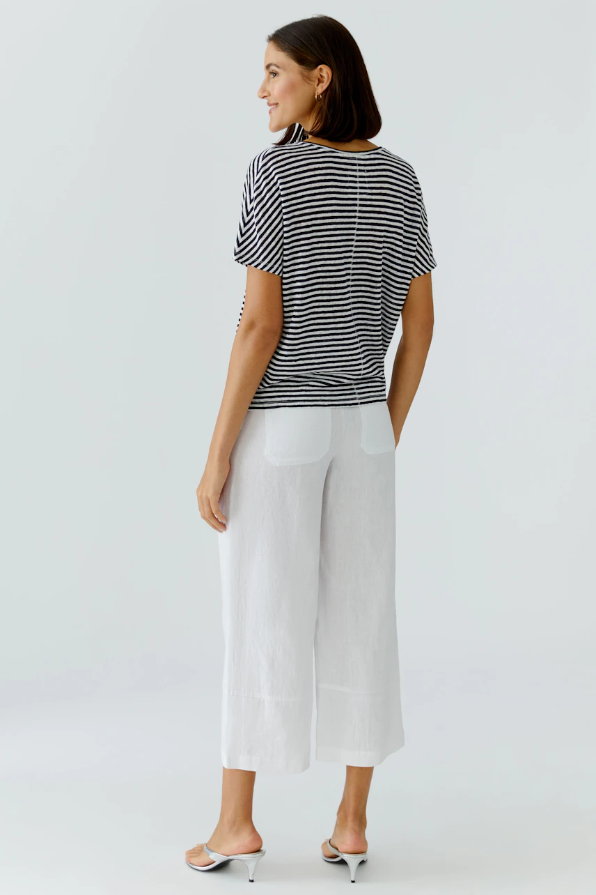 Casual women's T-shirt: Woman in striped T-shirt and white pants, standing confidently.