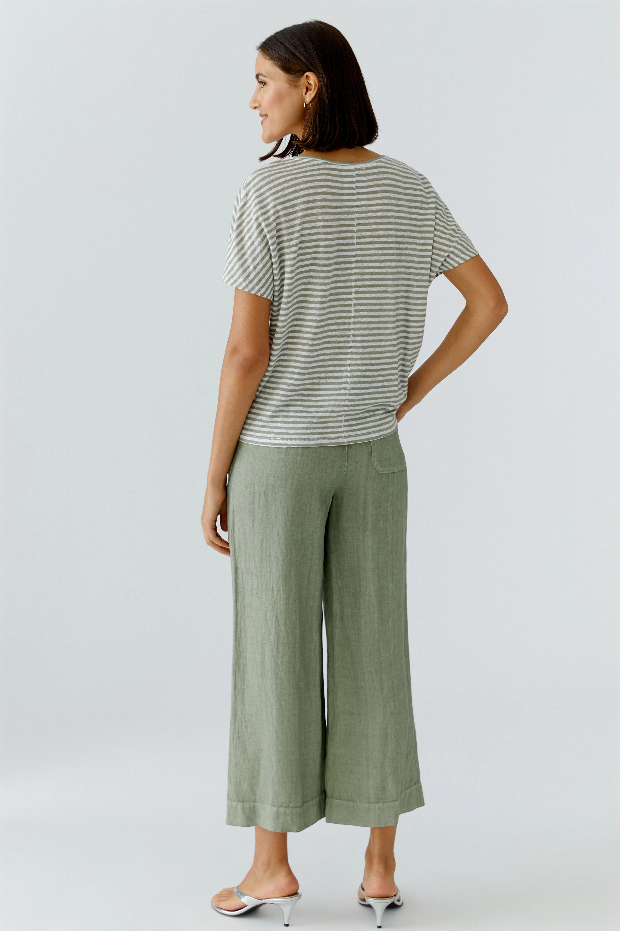 Casual women's T-shirt: Woman in striped T-shirt and green pants, standing confidently.
