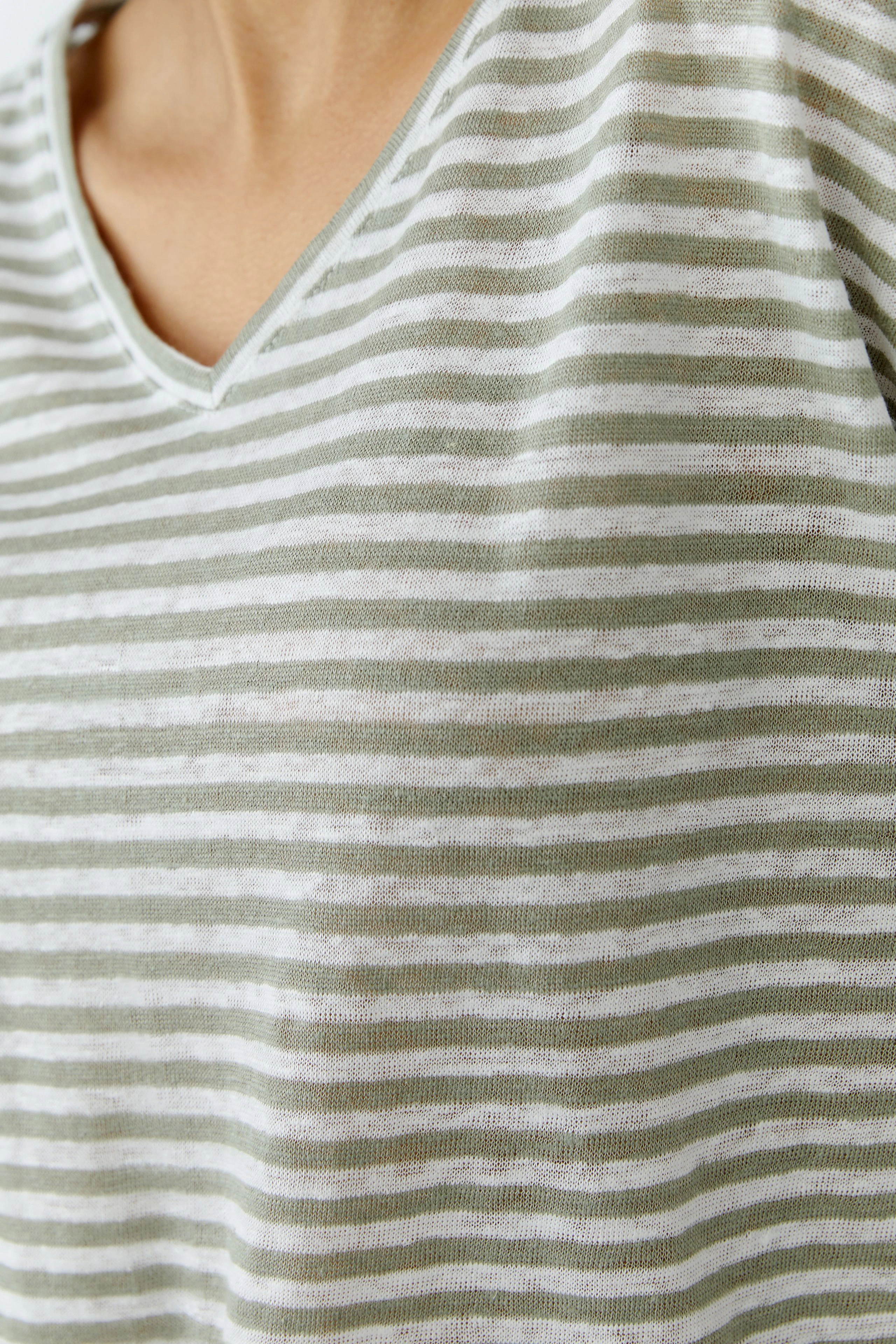 Striped T-shirt: Close-up of a woman's chest wearing a green and white striped T-shirt with a V-neck.