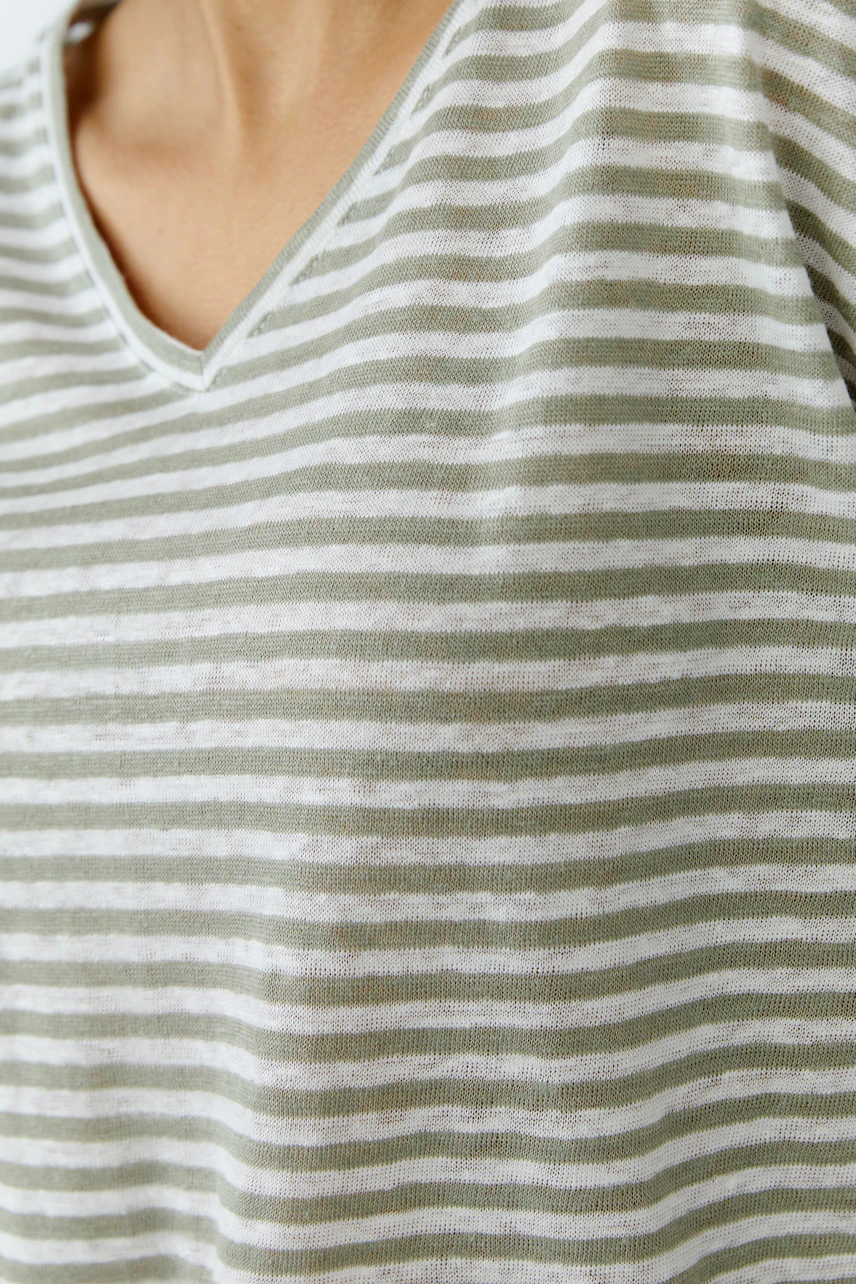 Striped T-shirt: Close-up of a woman's chest wearing a green and white striped T-shirt with a V-neck.