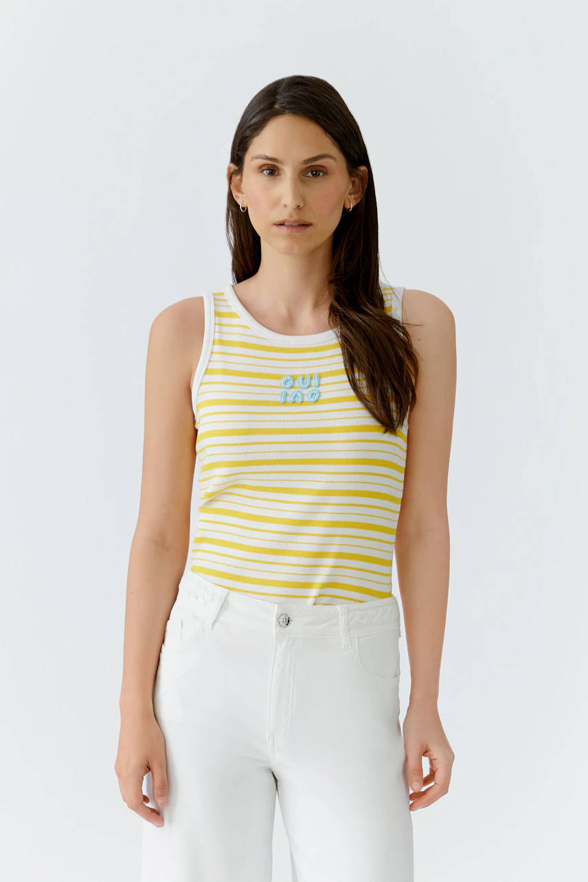 Gestreiftes Damen-Tank Top: Frau im gelb-weiß gestreiften Tank Top und weißen Hosen schaut direkt.