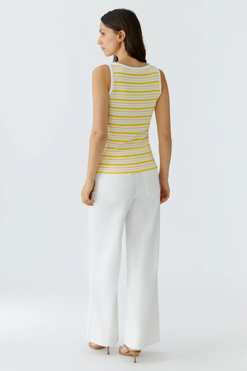 Damen-Tank Top: Frau im gelb-weiß gestreiften Tank Top und weißen Hosen, von hinten gesehen.