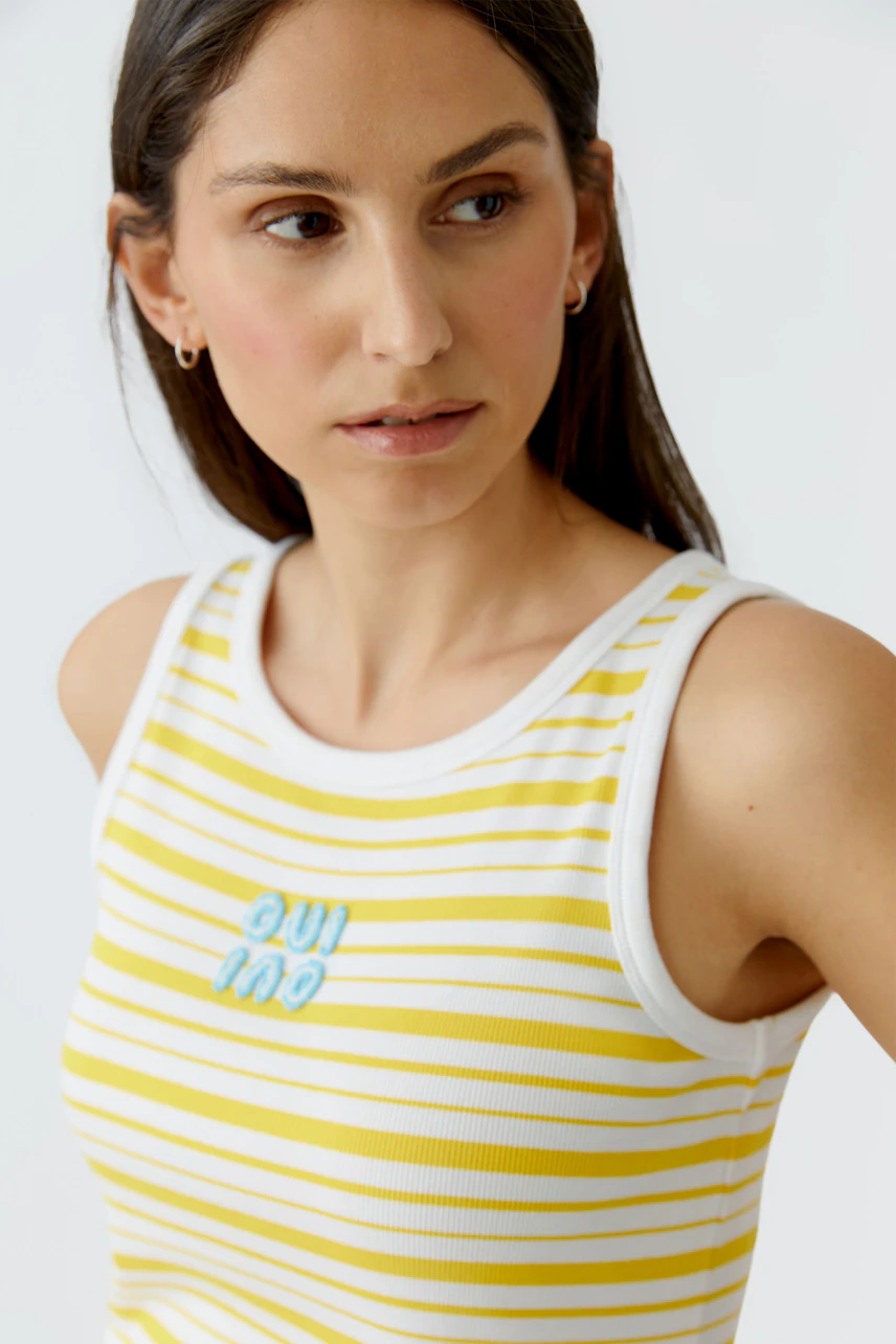Frau im gestreiften Tank Top: Gelb-weißes Streifenmuster mit "Oui"-Logo, lässiger Look.