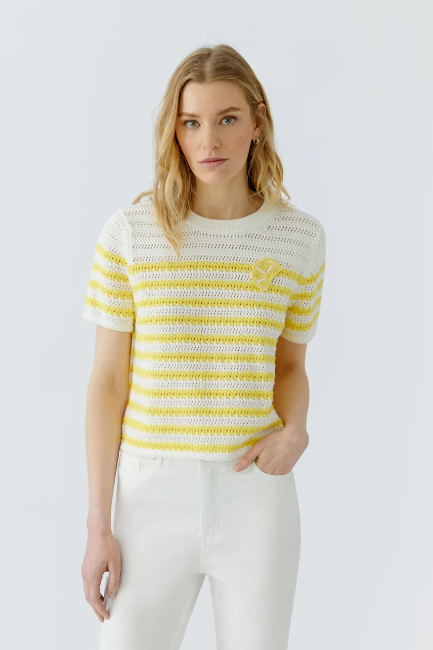 Damen-Pullover: Frau im gelb-weiß gestreiften Pullover, lässig kombiniert mit weißen Hosen.