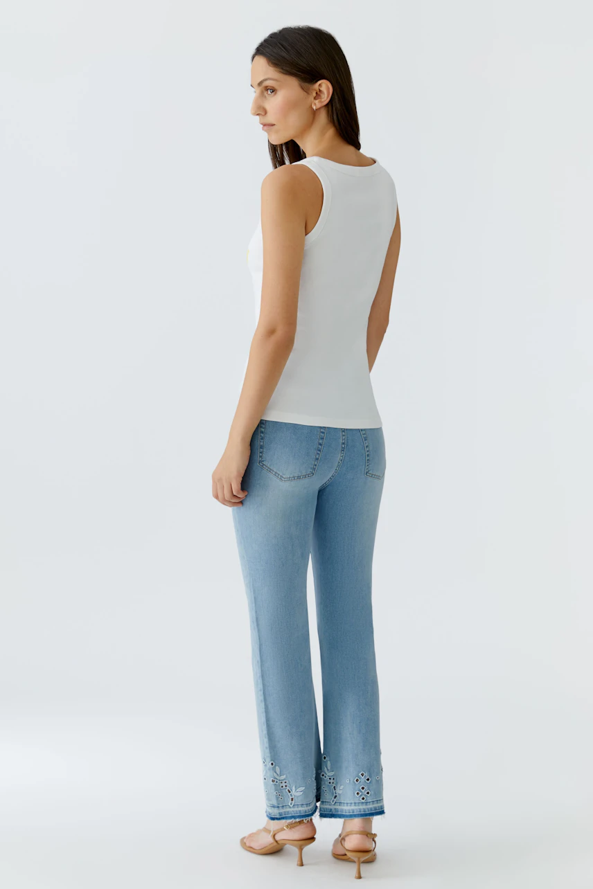 Weißes Tank Top: Frau in schlichtem, ärmellosem Oberteil und blauer Jeans von hinten zu sehen.
