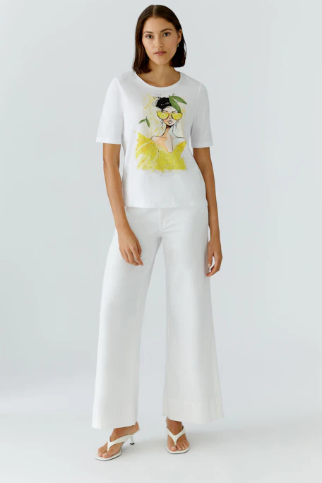 White T-shirt with artistic print of a woman in yellow, featuring short sleeves and a round neckline.