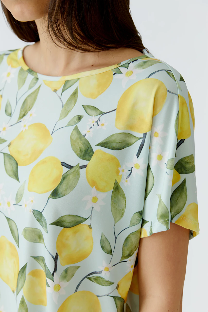 Damen-T-Shirt: Frau im T-Shirt mit Zitronen-Print und kurzen Ärmeln, frischer Sommerlook.