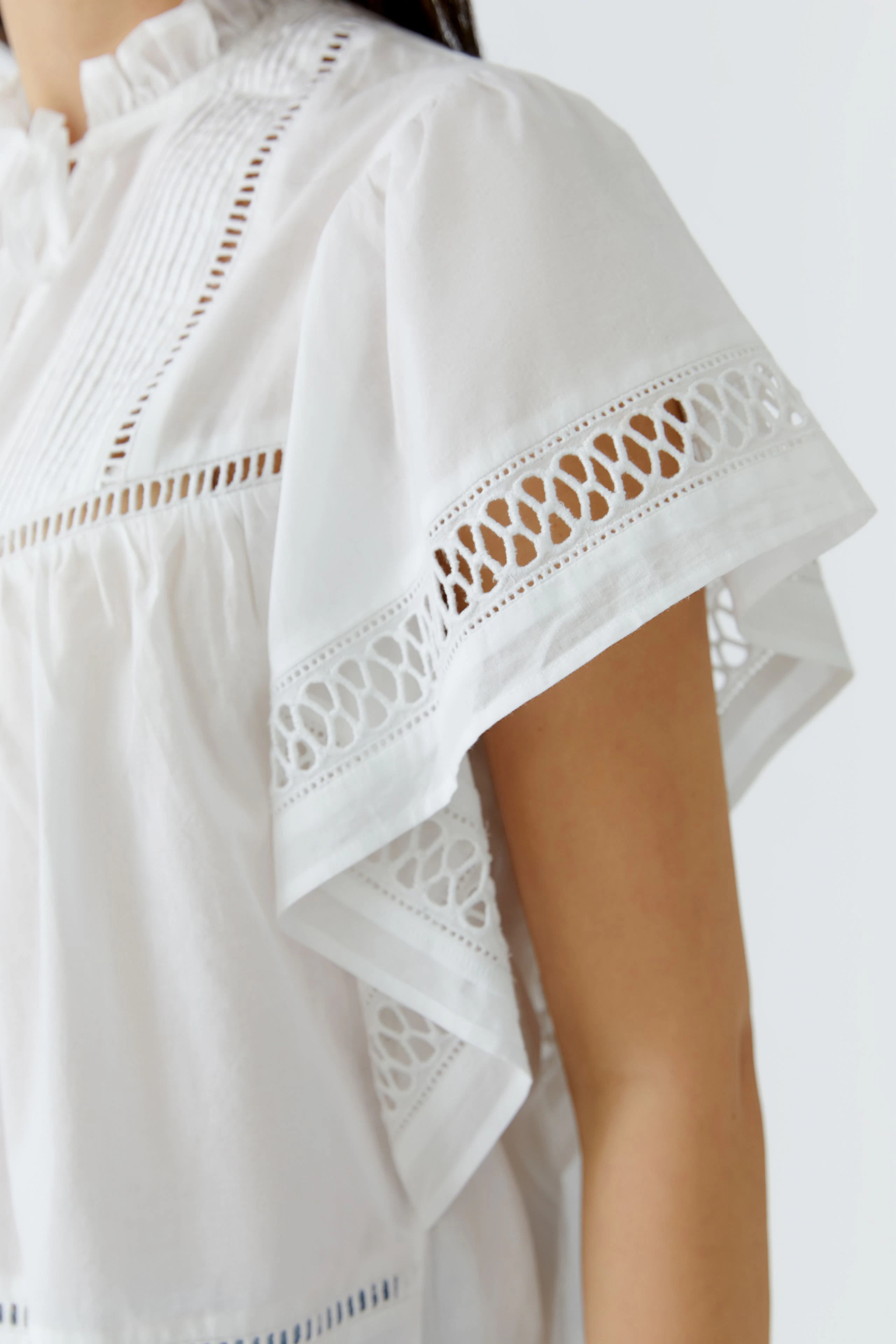 White blouse with lace details: Woman in a short-sleeved blouse featuring intricate lace patterns.