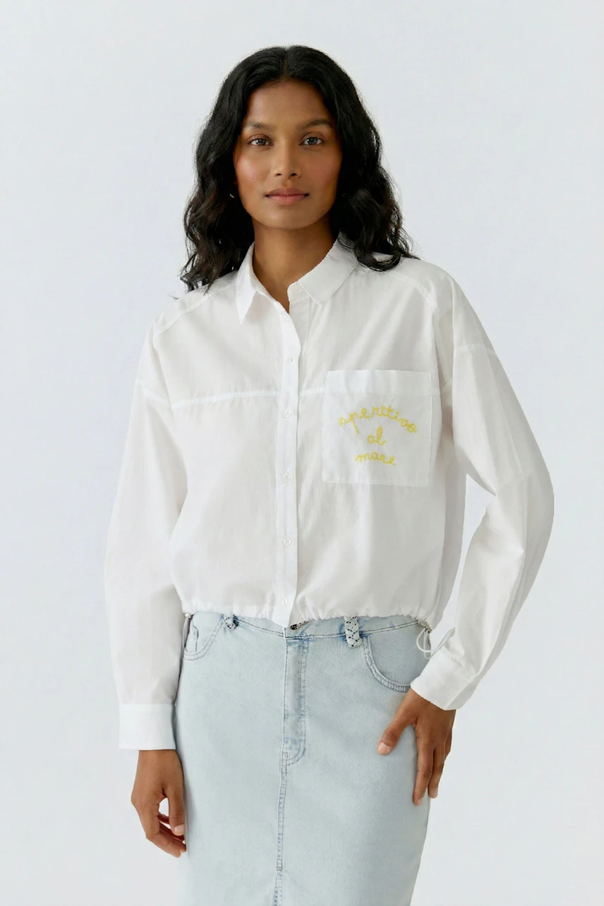 Casual shirt blouse: Woman in a white blouse with yellow embroidery, paired with a light denim skirt.