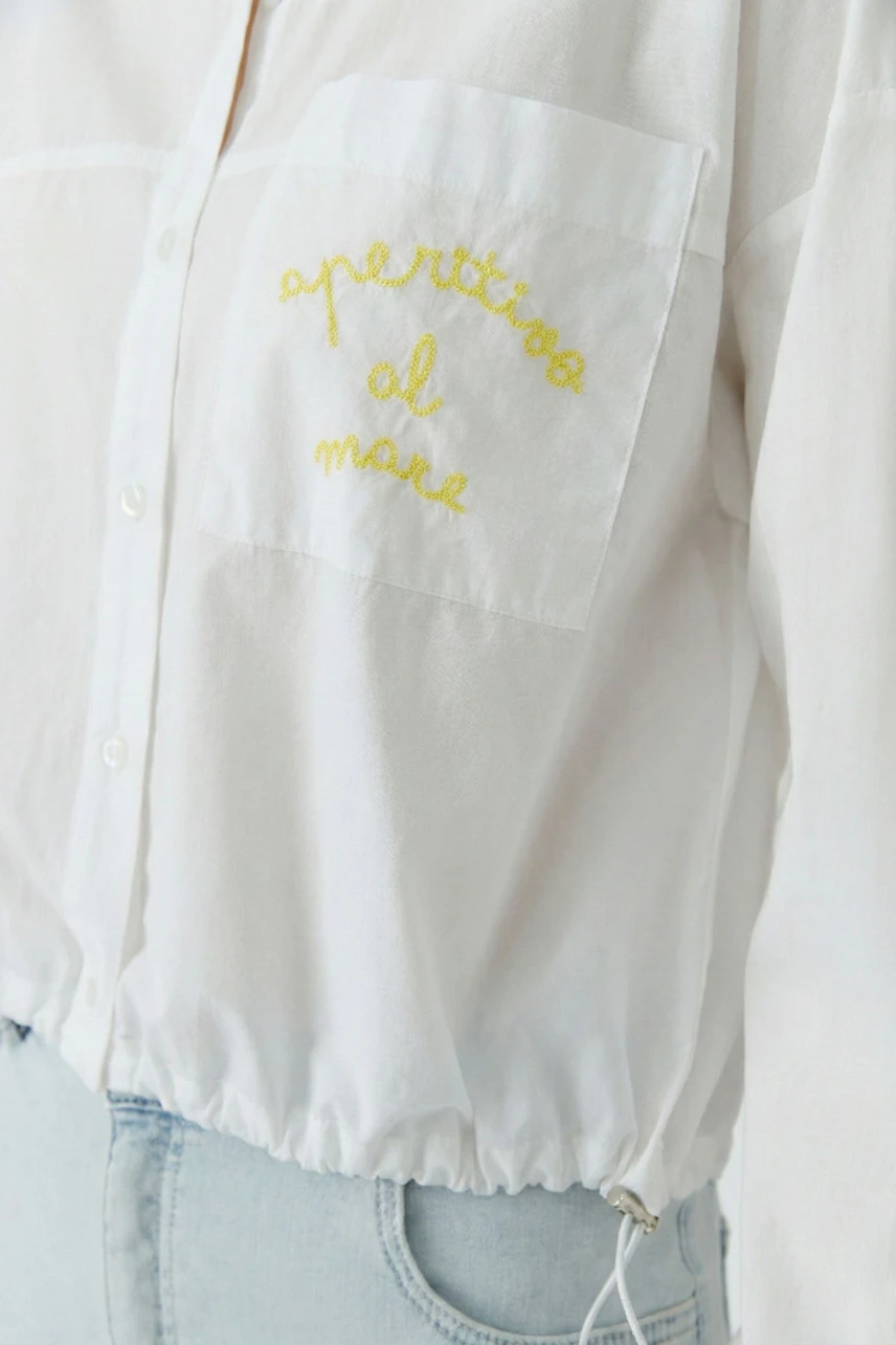 Casual women's shirt blouse: White blouse with yellow embroidery, worn by a woman with light blue jeans.