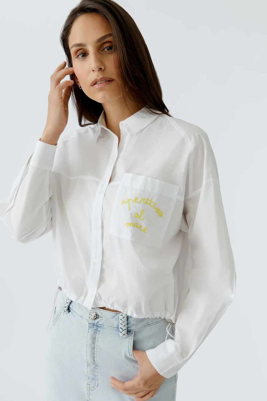Casual shirt blouse: Woman in white blouse with yellow embroidery, paired with light denim jeans.